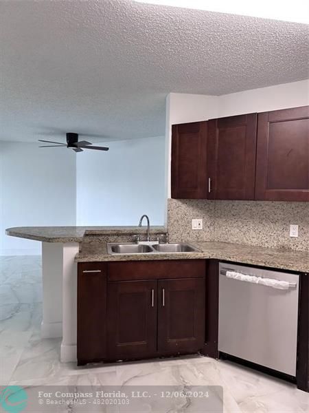 a kitchen with granite countertop a sink and cabinets