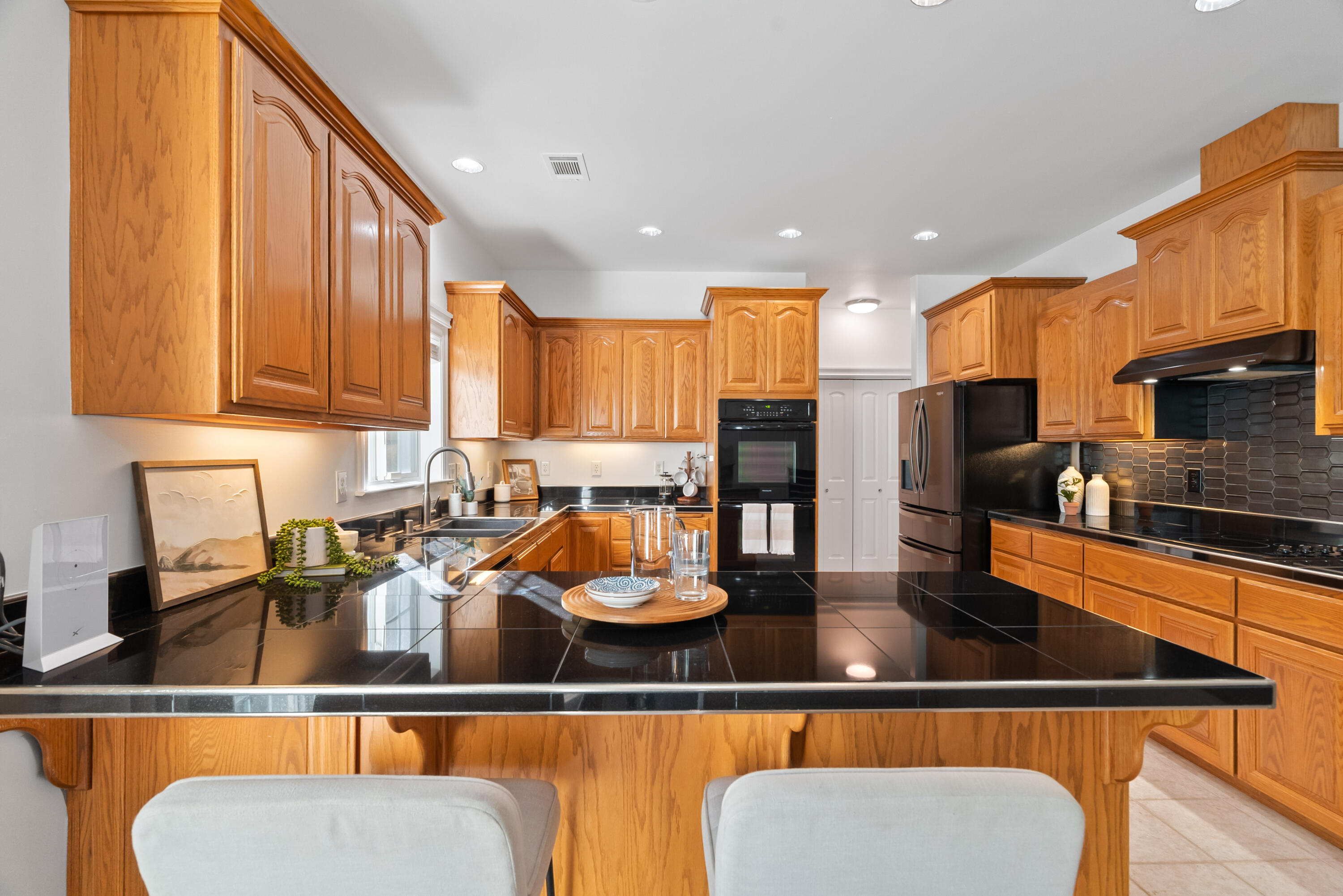 a kitchen with stainless steel appliances granite countertop a refrigerator a stove top oven and a sink