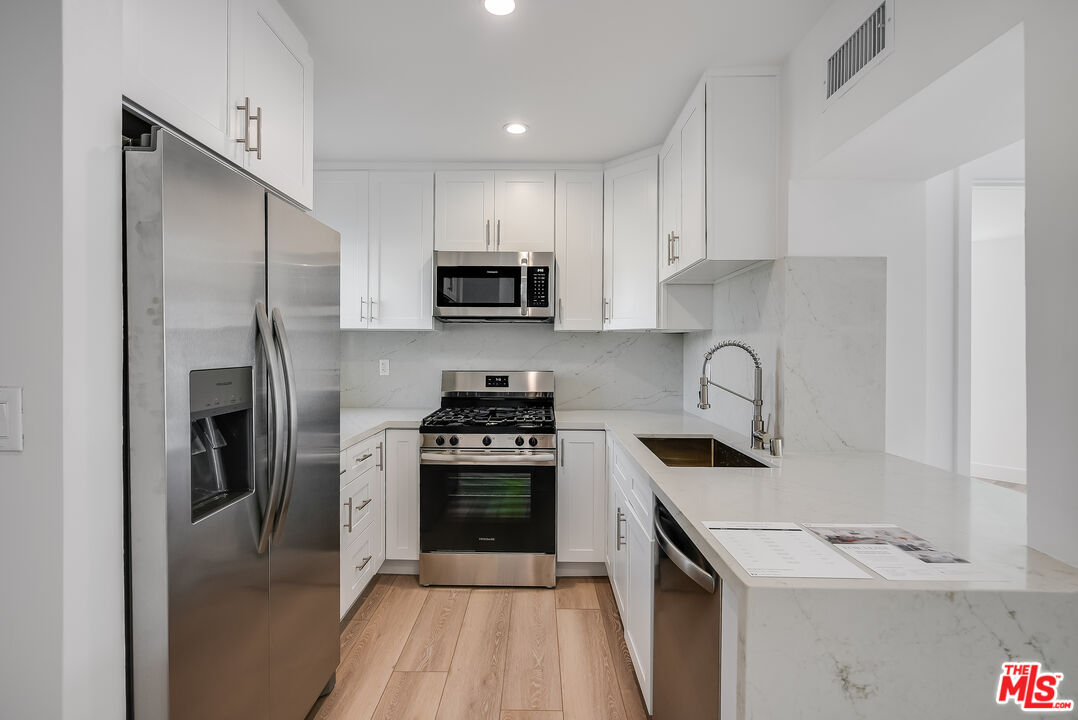 a kitchen with stainless steel appliances granite countertop a refrigerator sink and stove