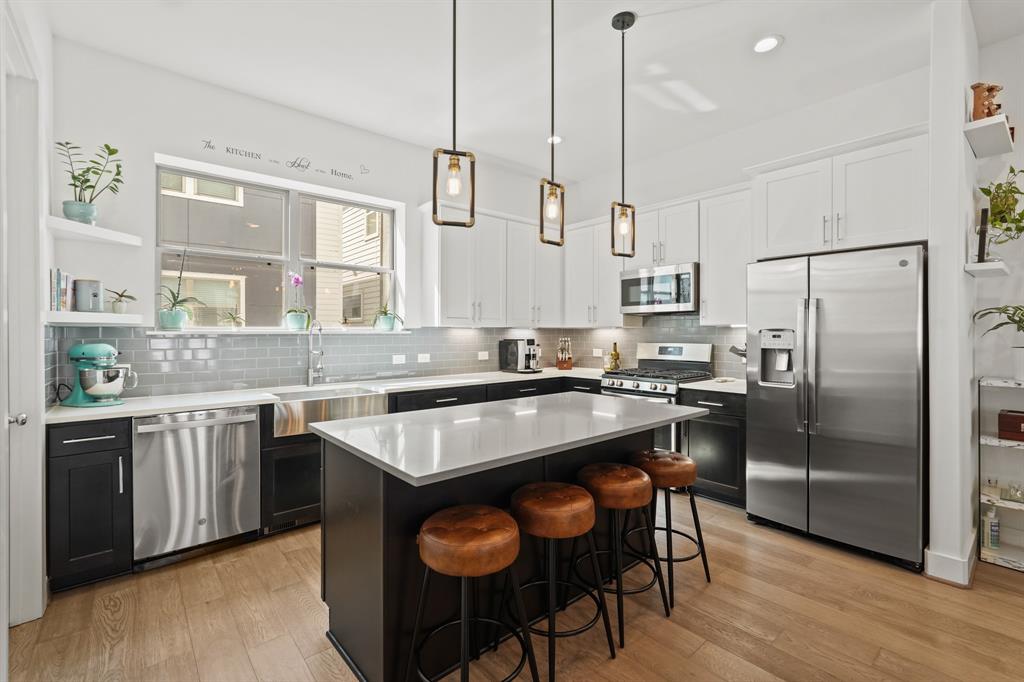 a kitchen with stainless steel appliances granite countertop a table chairs stove and refrigerator