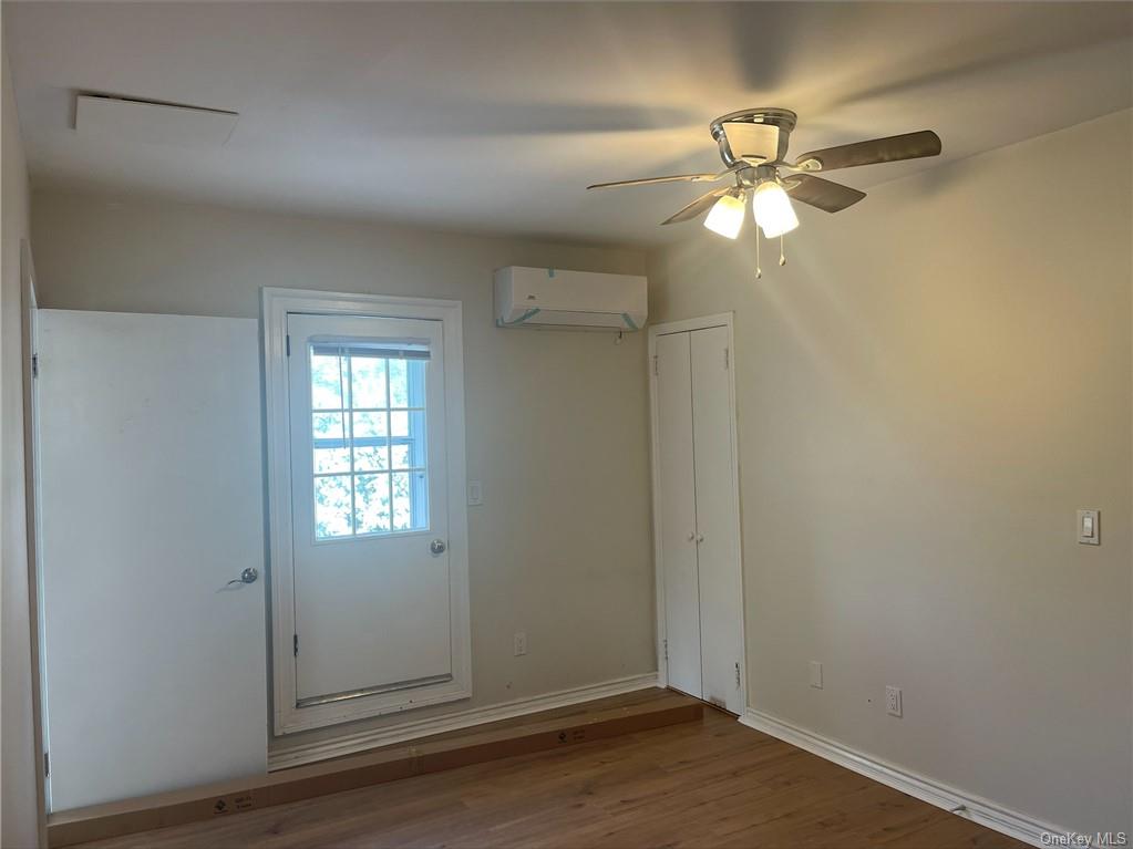 Doorway with wood-type flooring, ceiling fan, and a wall mounted AC