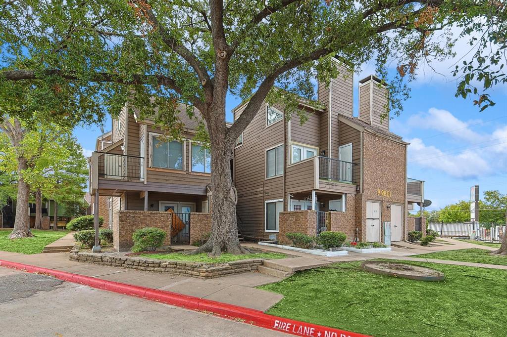 a front view of a residential apartment building with yard and green space