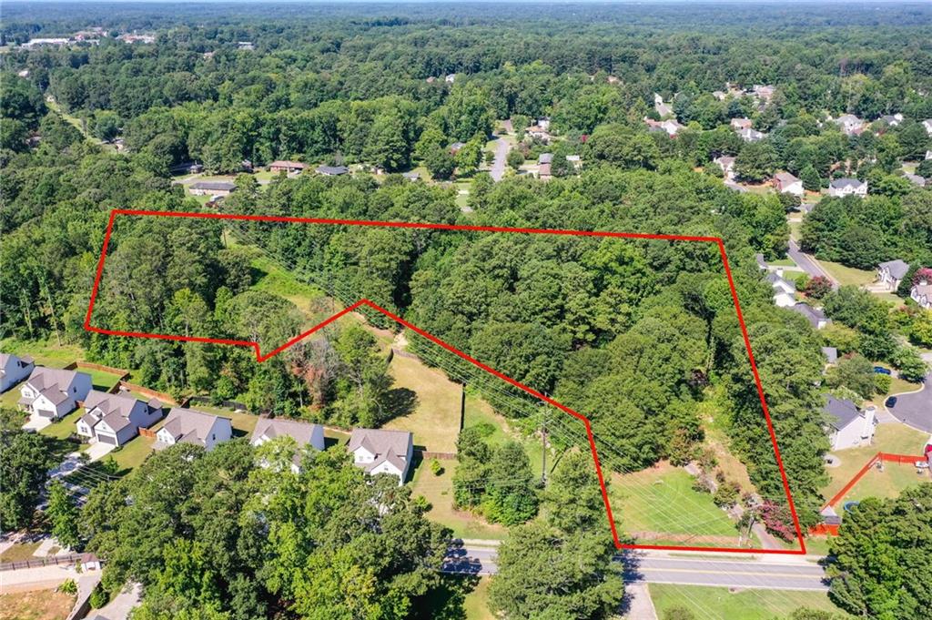 an aerial view of residential house with outdoor space and trees all around