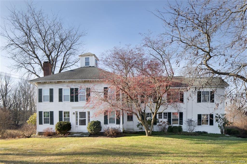 a front view of a building with large trees