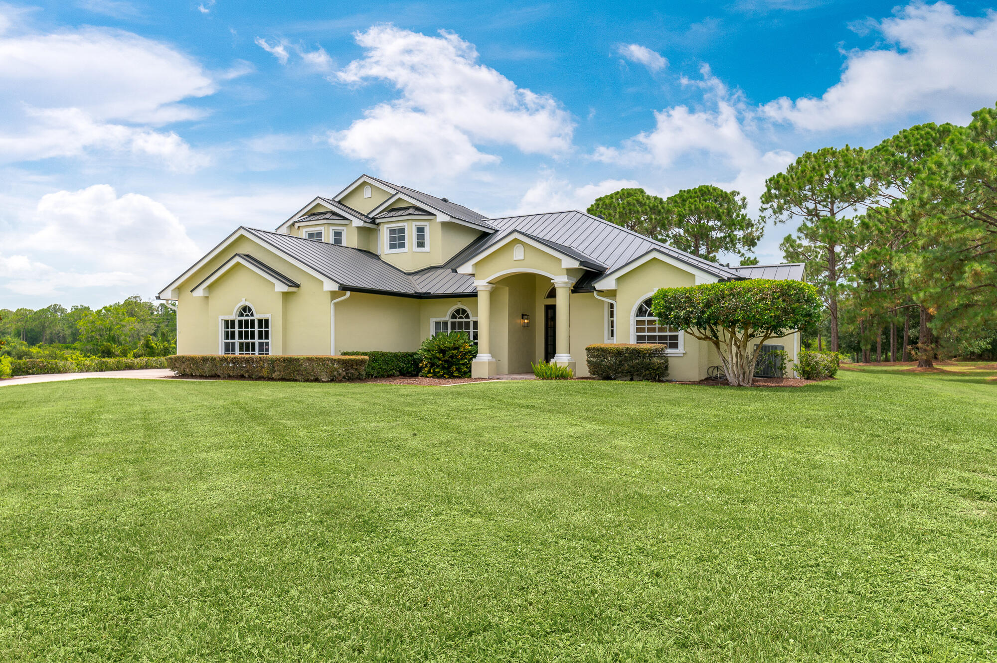 a view of a house with a big yard and large trees