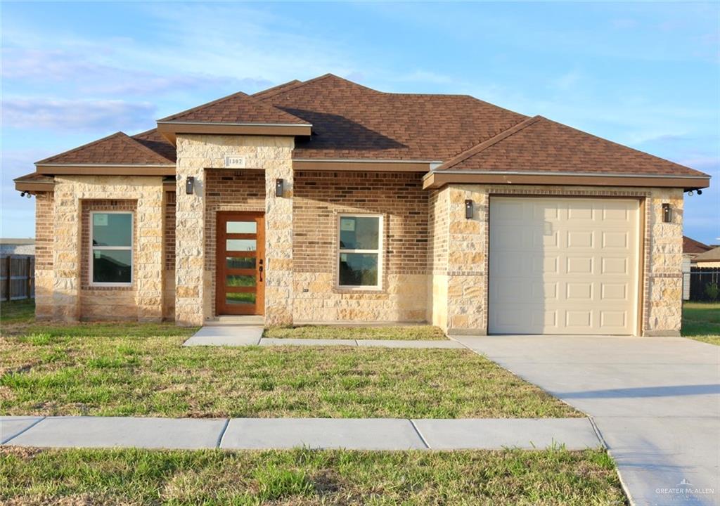 View of front facade featuring a front lawn and a garage