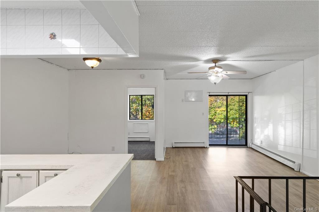 Living room featuring a wealth of natural light, light wood-type flooring, and a baseboard heating unit