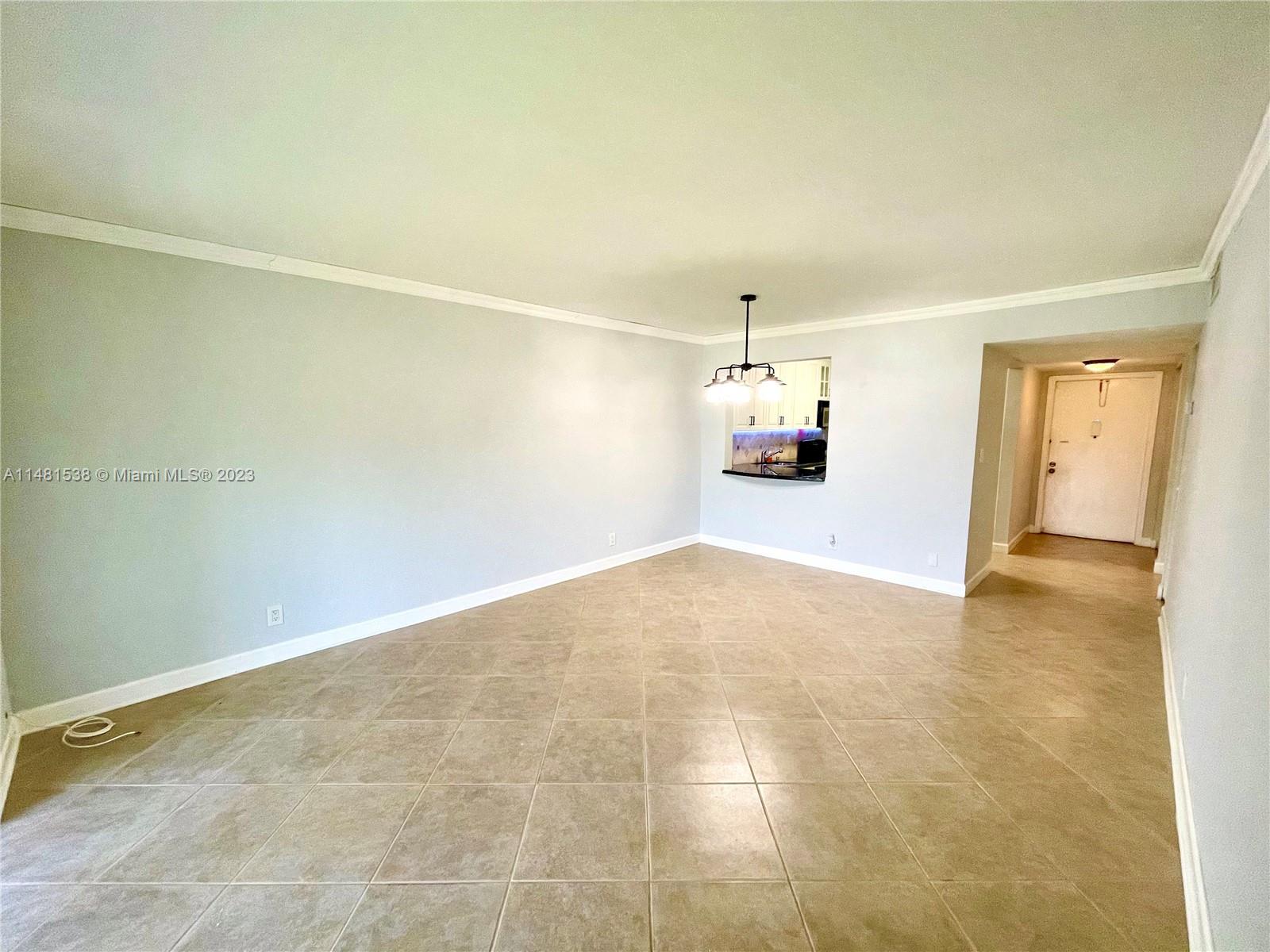 an empty room with a chandelier fan and windows