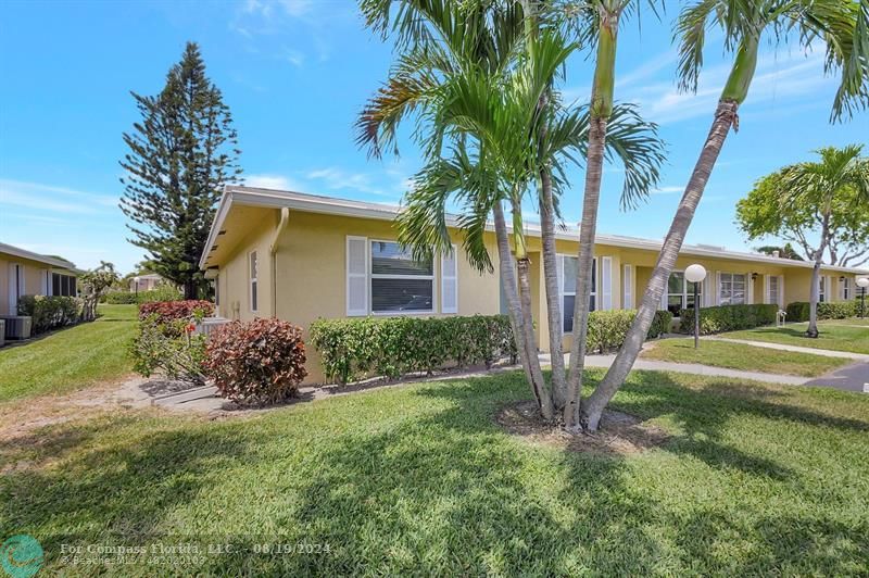 a view of a house with a yard and palm trees