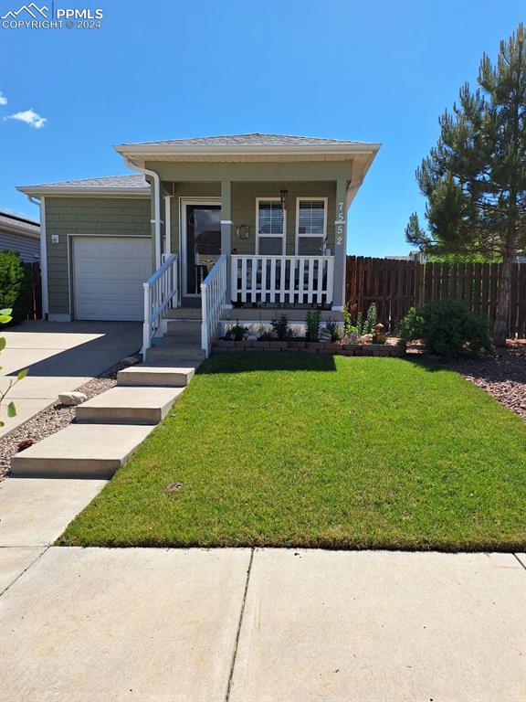 Ranch-style house featuring a garage, a front yard, and covered porch