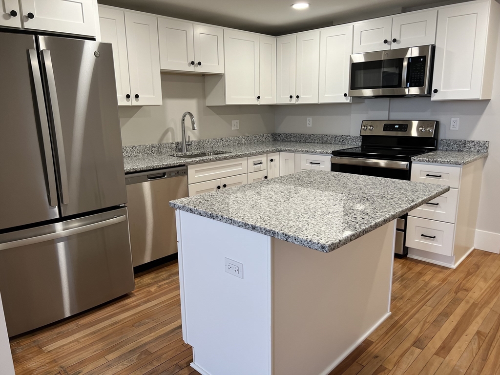 a kitchen with granite countertop a refrigerator stove and microwave