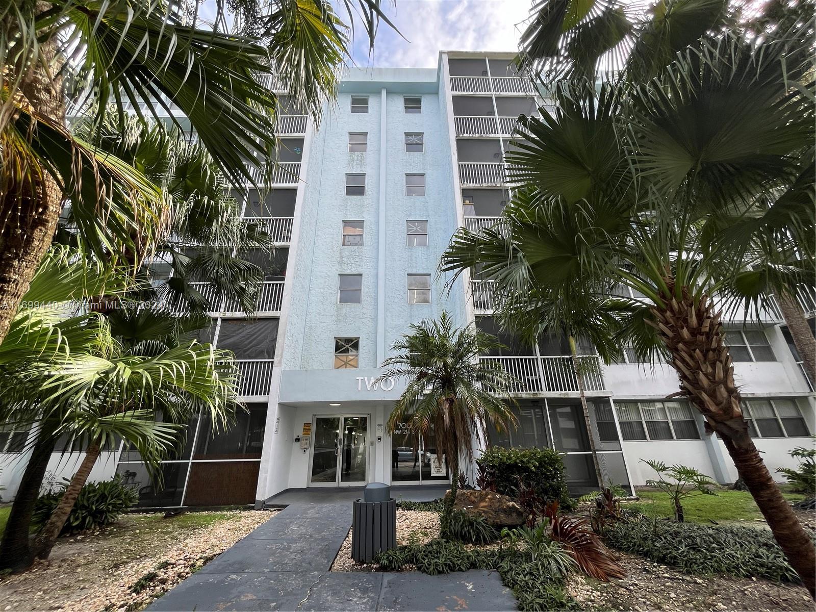 a front view of multi story residential apartment building with yard and green space