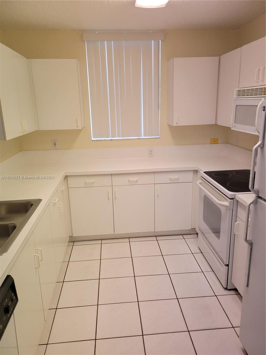 a kitchen with granite countertop white cabinets and white appliances