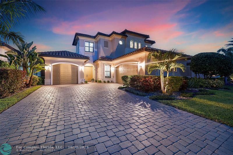 Osprey Lake newer home elevation at night time view with front pavered driveway & 3 car garages