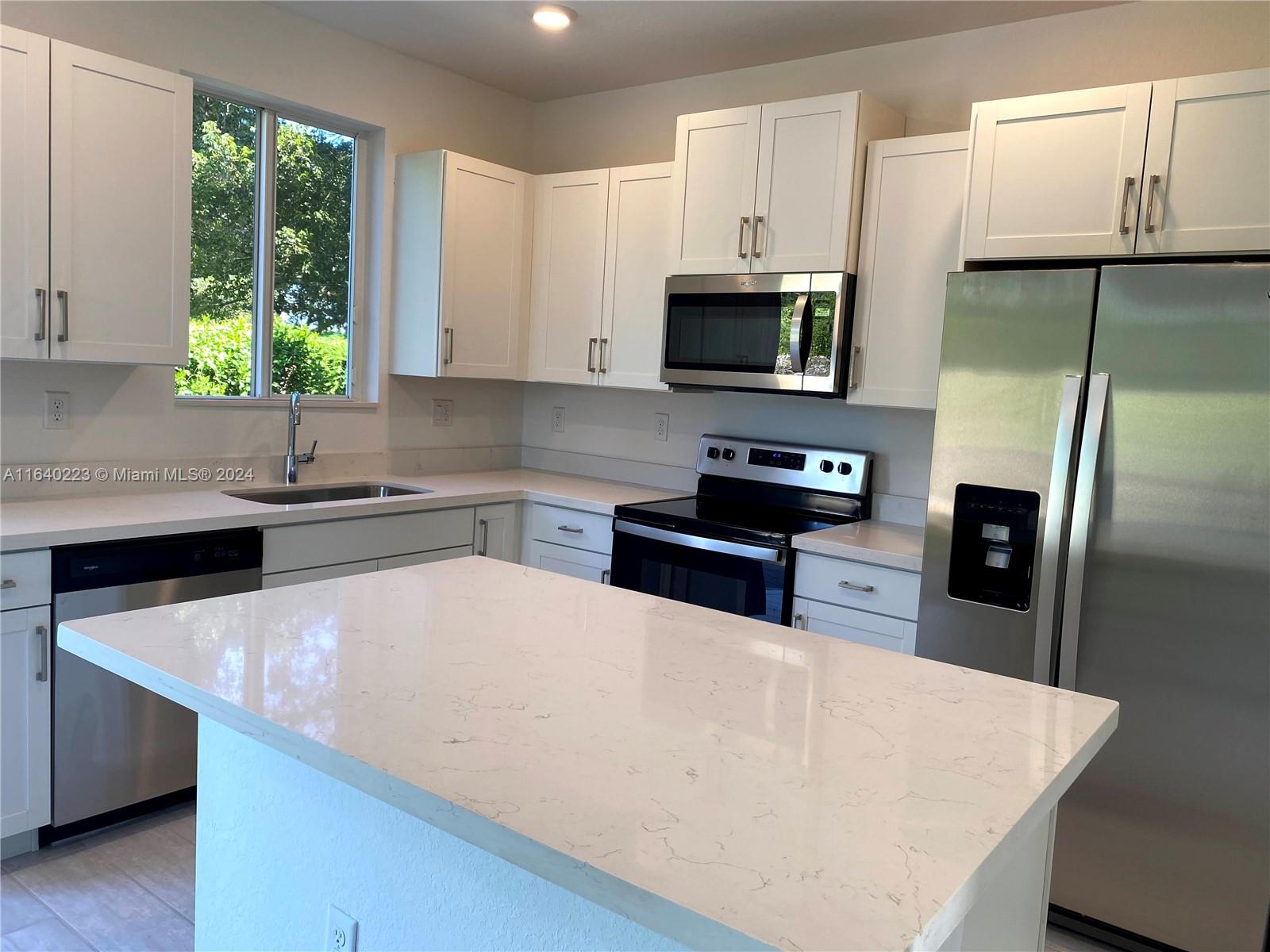 a kitchen with stainless steel appliances a microwave sink refrigerator and cabinets