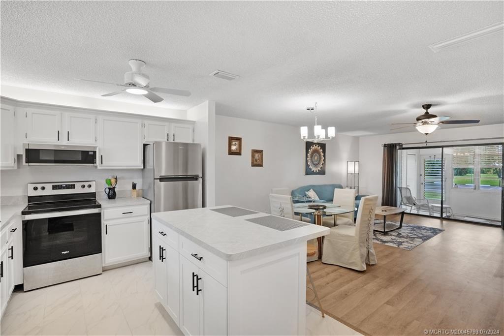 a living room with stainless steel appliances kitchen island furniture and a kitchen view