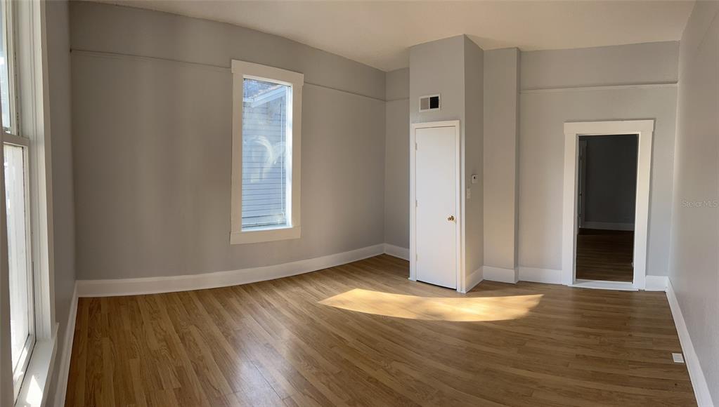 an empty room with wooden floor and windows