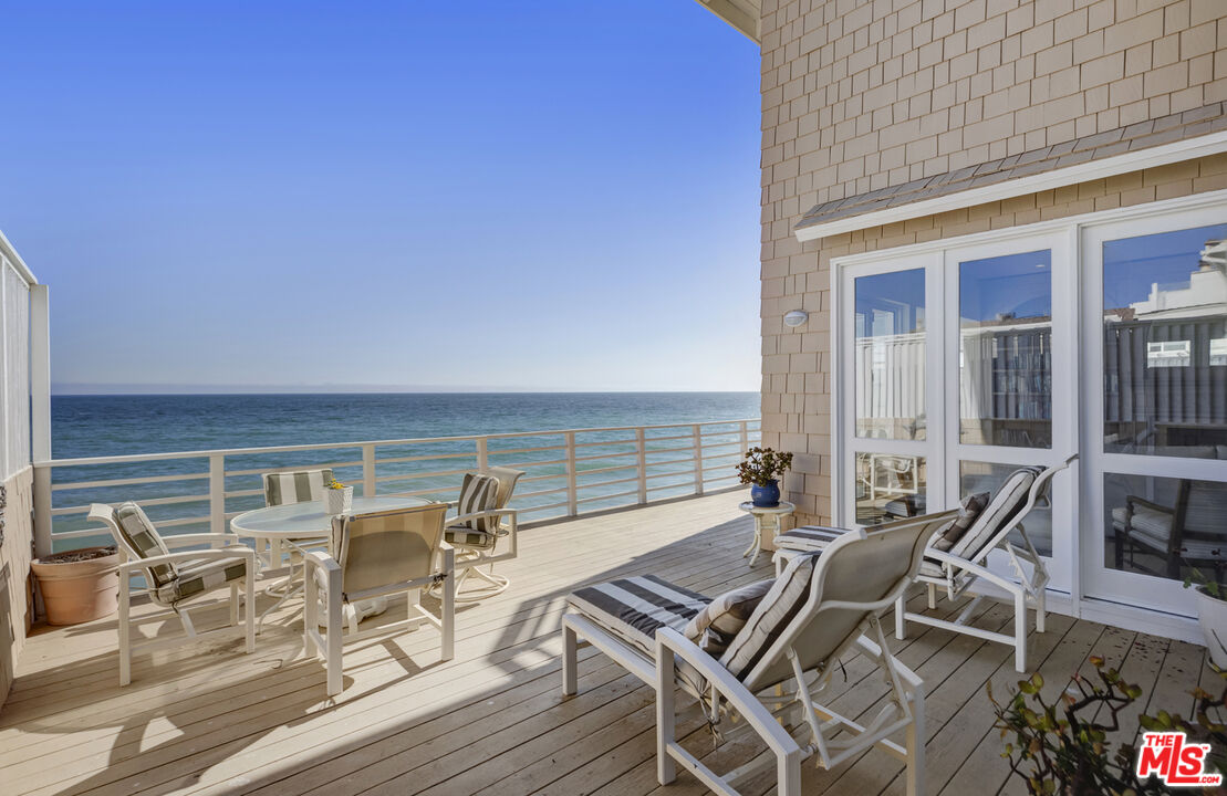 a view of a patio with lawn chairs floor to ceiling window and an outdoor kitchen