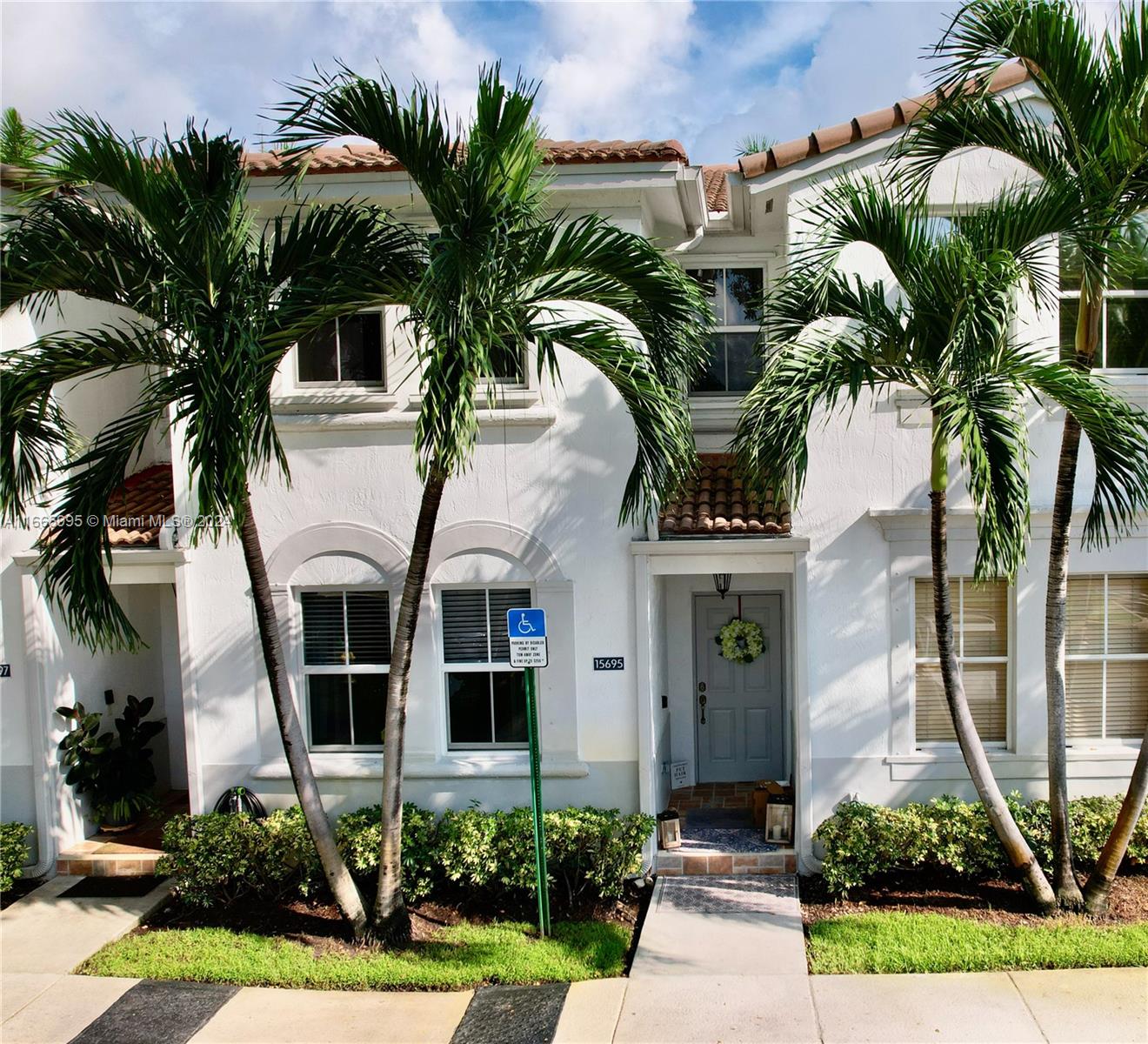 a front view of multi story residential apartment building with yard and parking