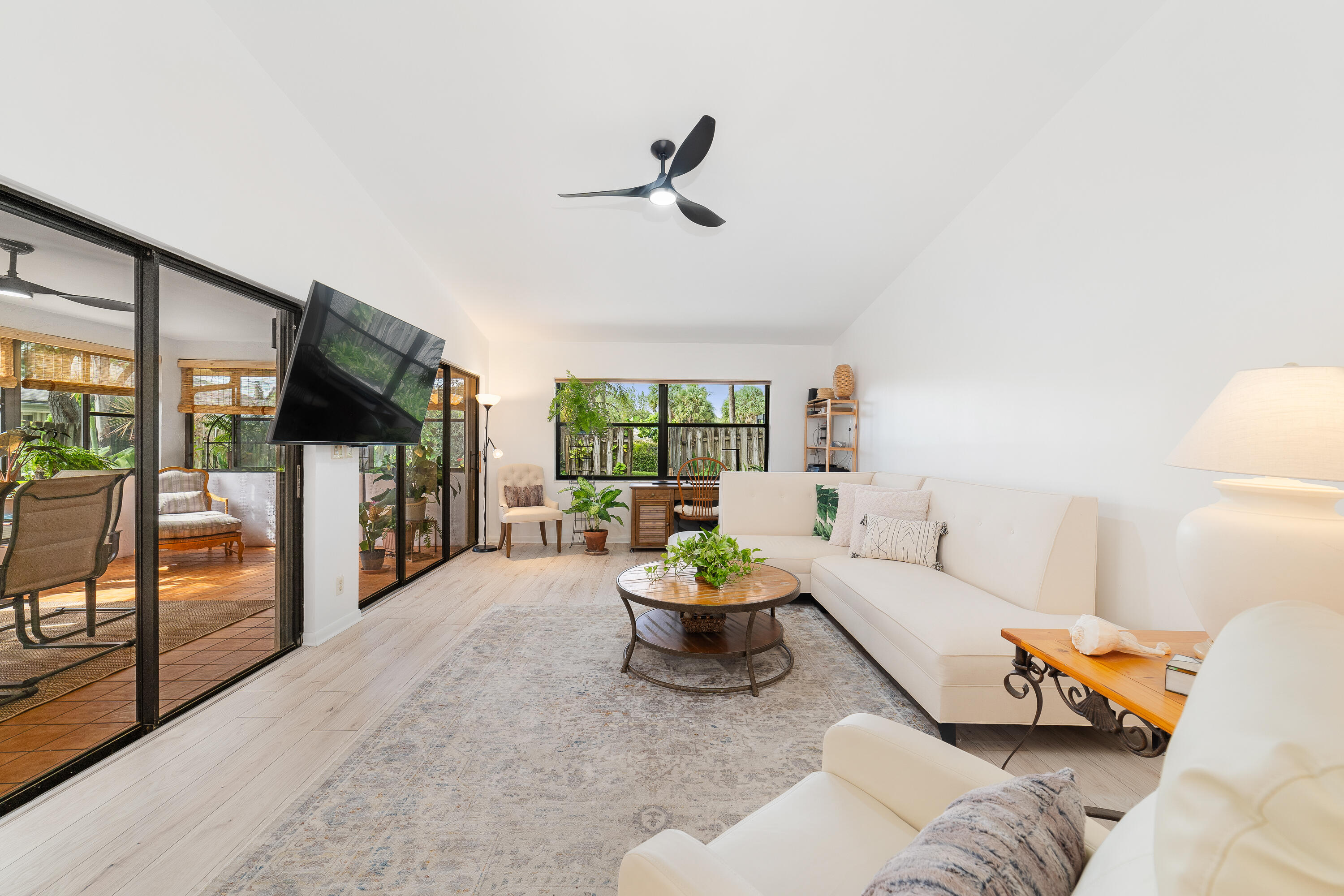 a living room with furniture a flat screen tv and a floor to ceiling window