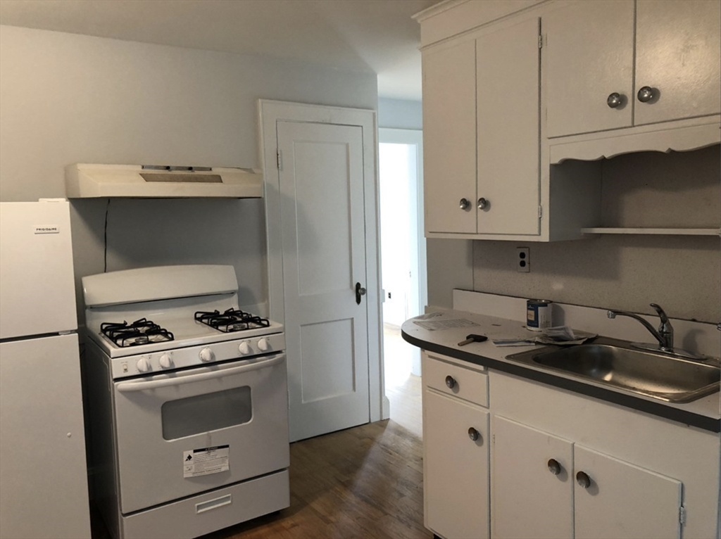 a kitchen with granite countertop white cabinets and white stove