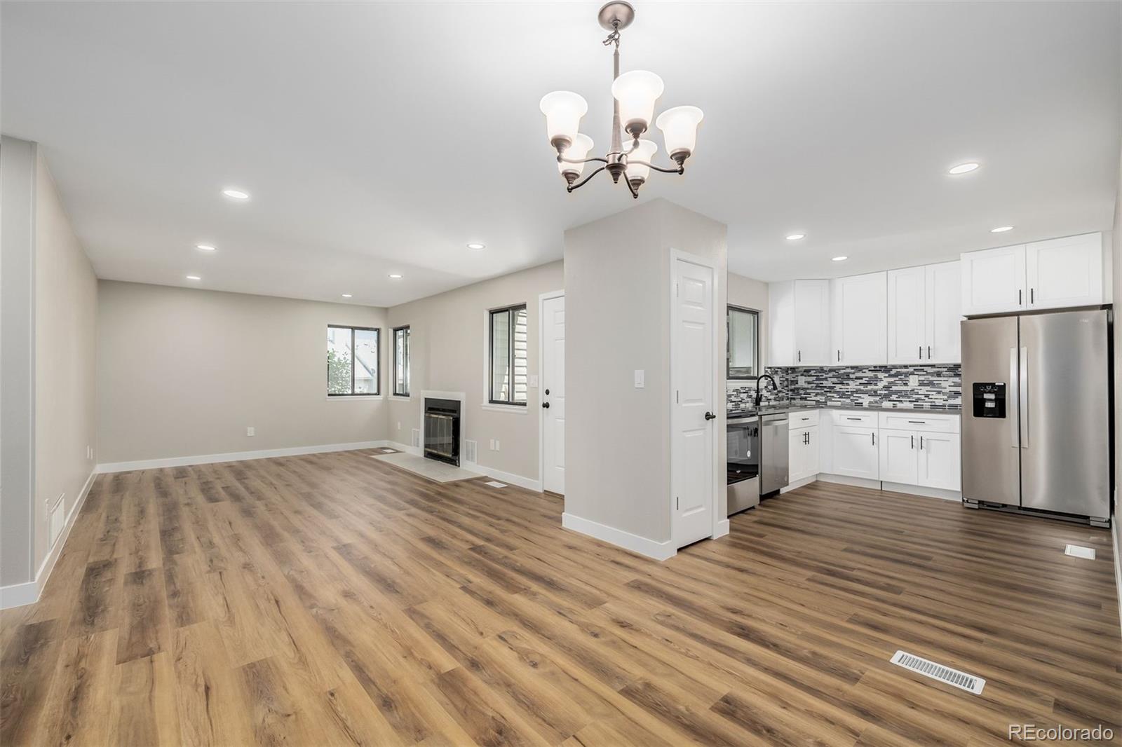 a view of a kitchen with a refrigerator and wooden floor