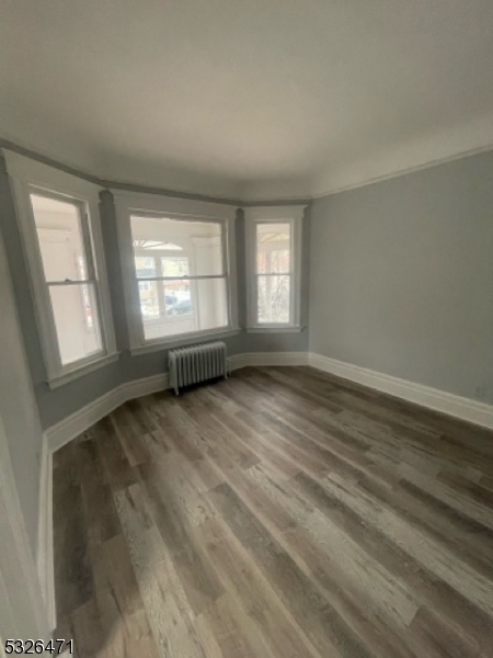 a view of an empty room with wooden floor and window