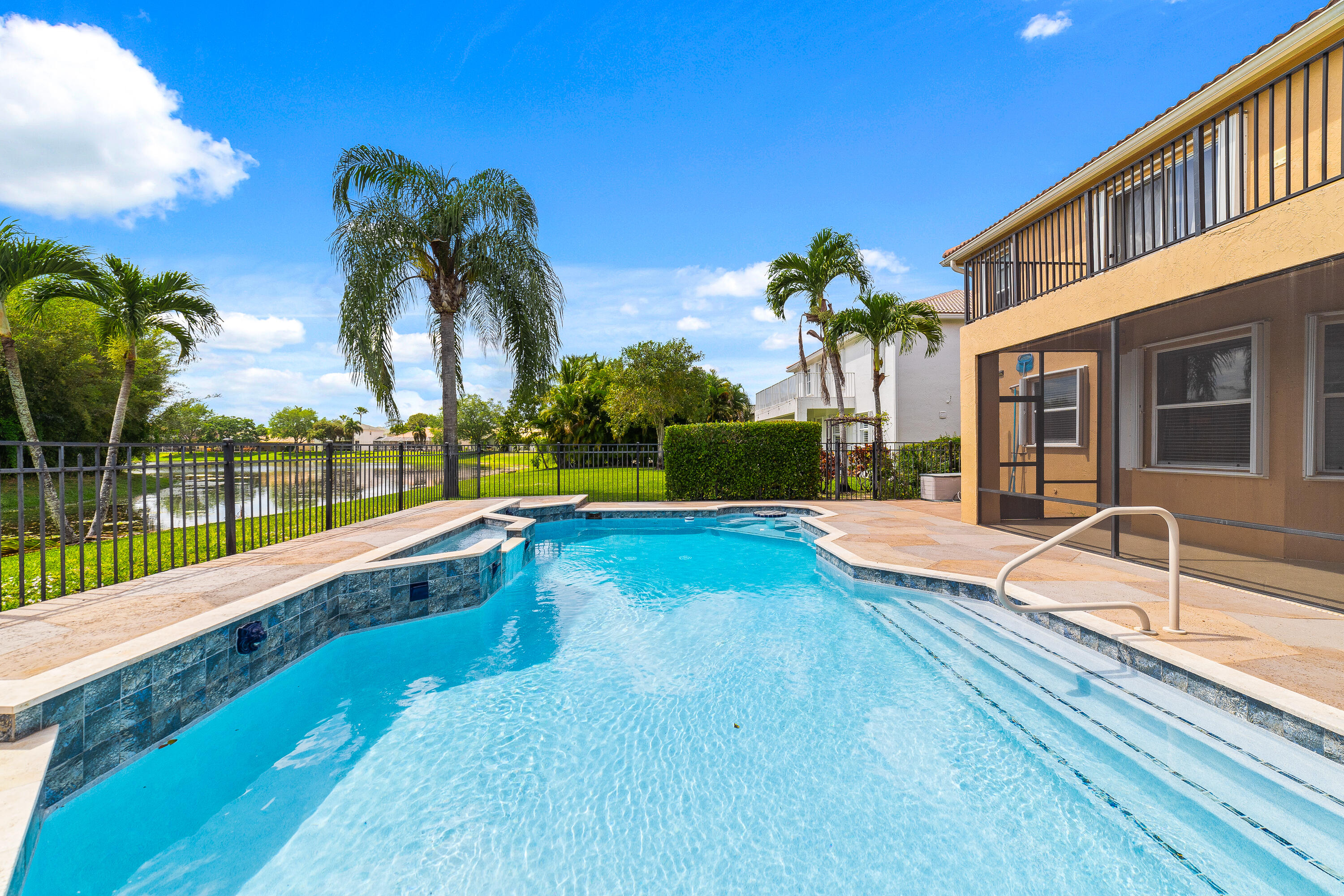 a view of swimming pool with a bench and palm trees