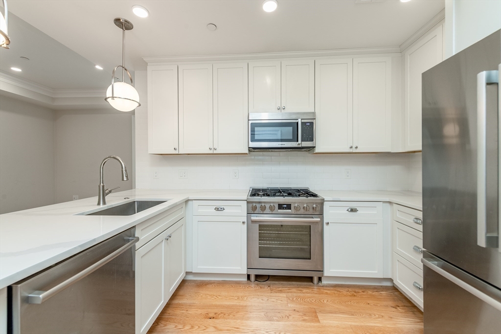 a kitchen with stainless steel appliances granite countertop a sink a stove and a refrigerator