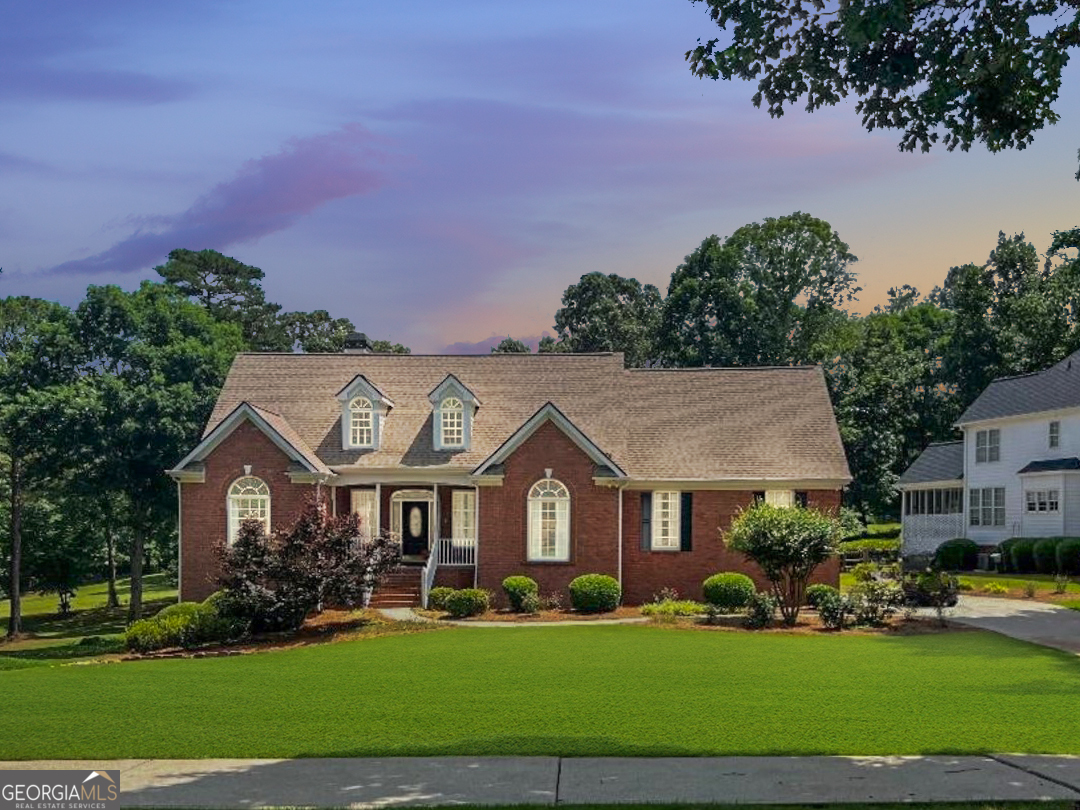 a view of a brick house with a big yard and large trees