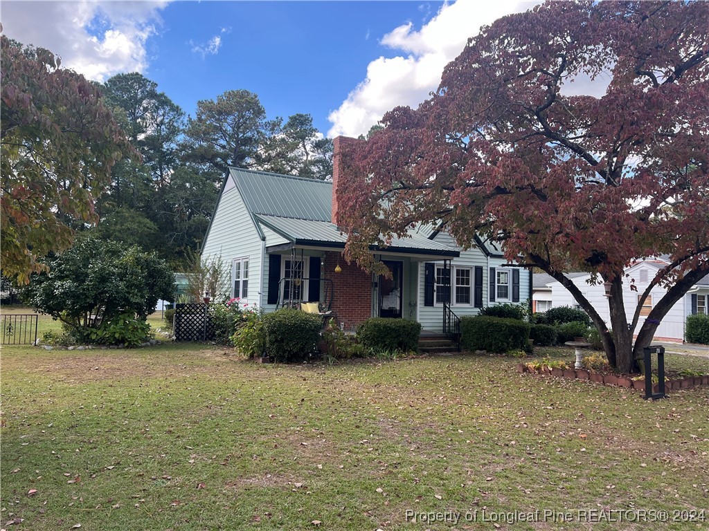 a front view of a house with a garden and tree