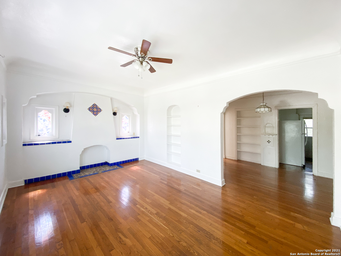 a view of empty room with wooden floor and fan