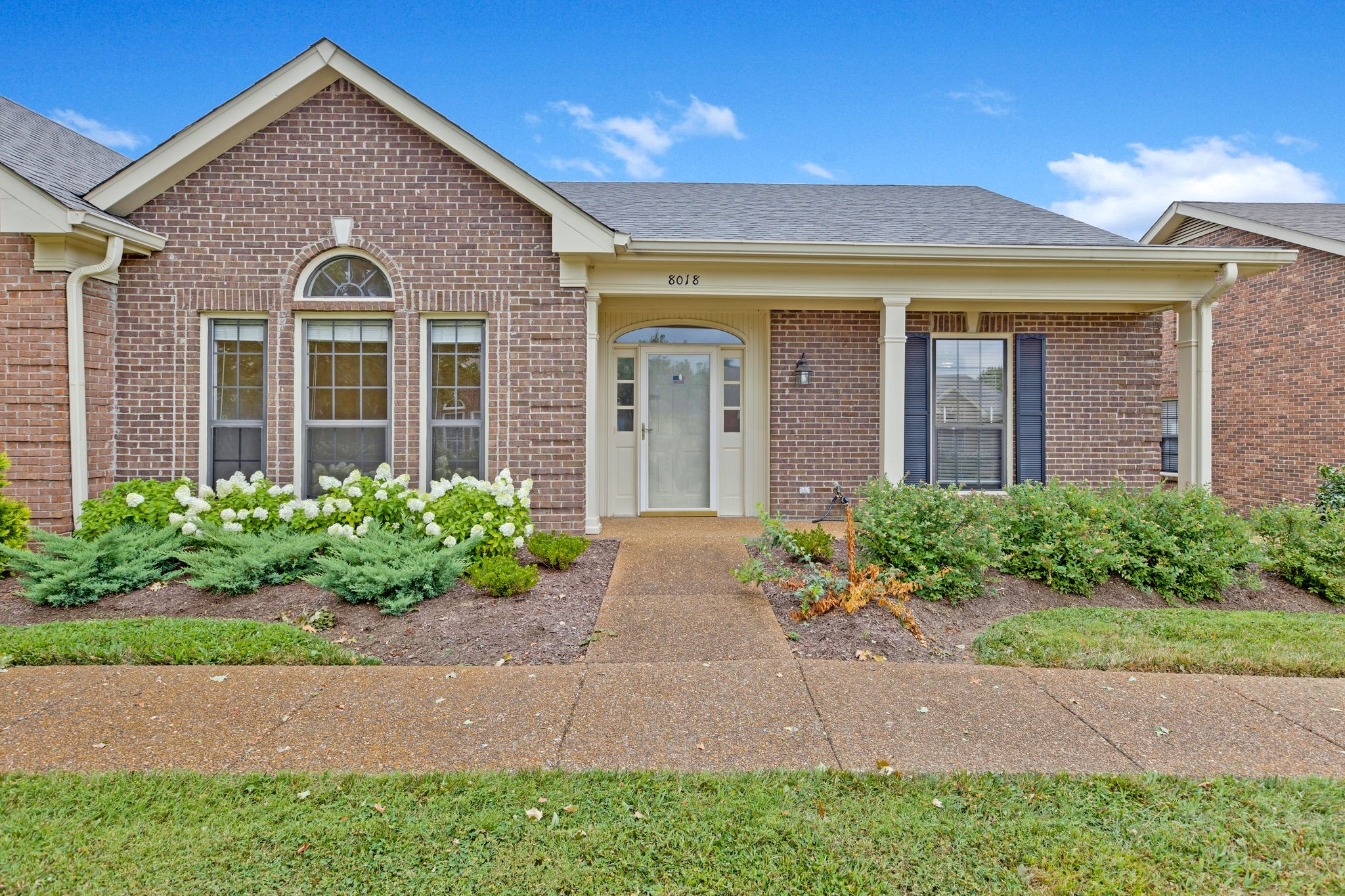 a view of a brick house with a yard and plants