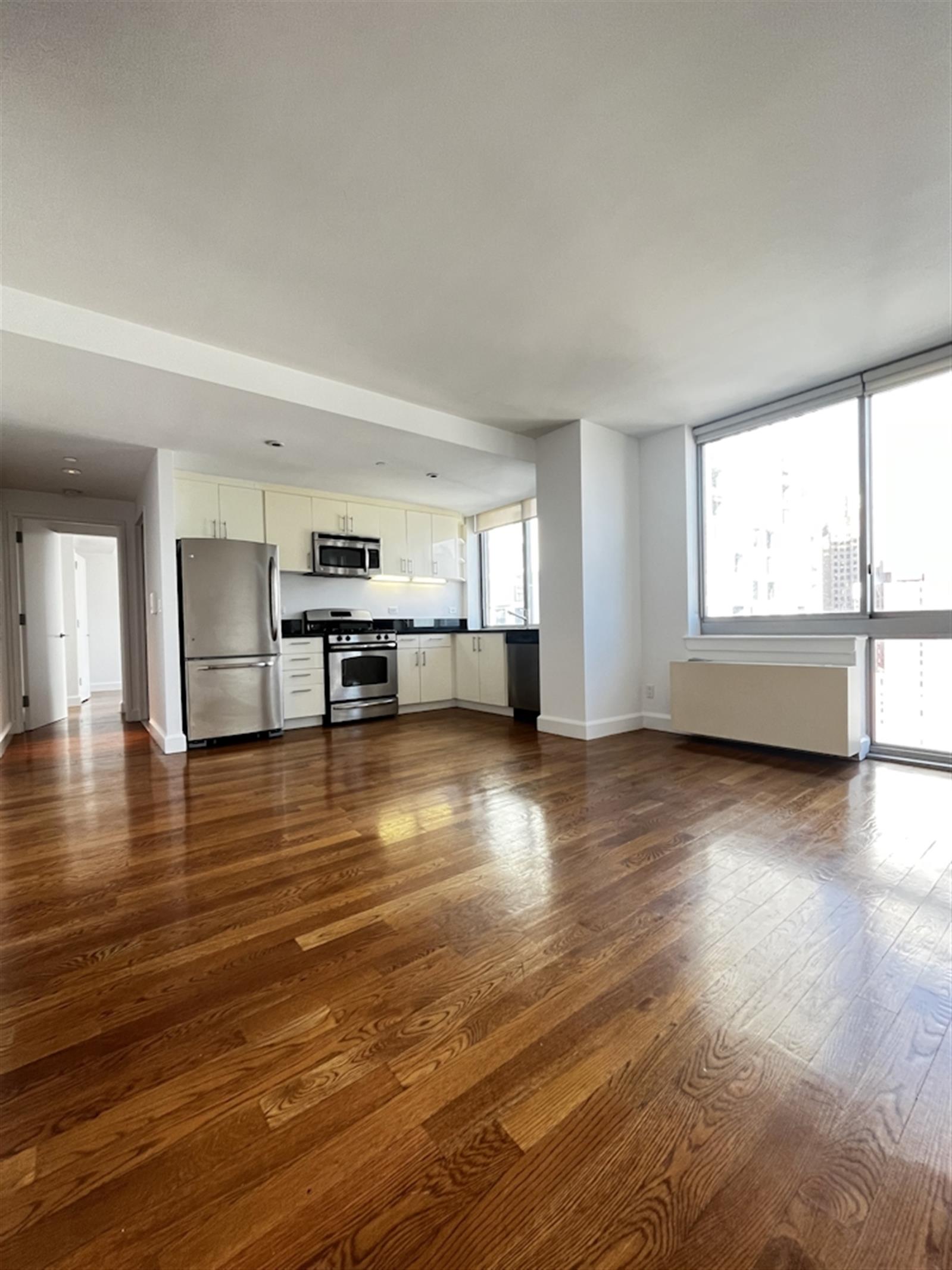 a view of empty room with kitchen and window