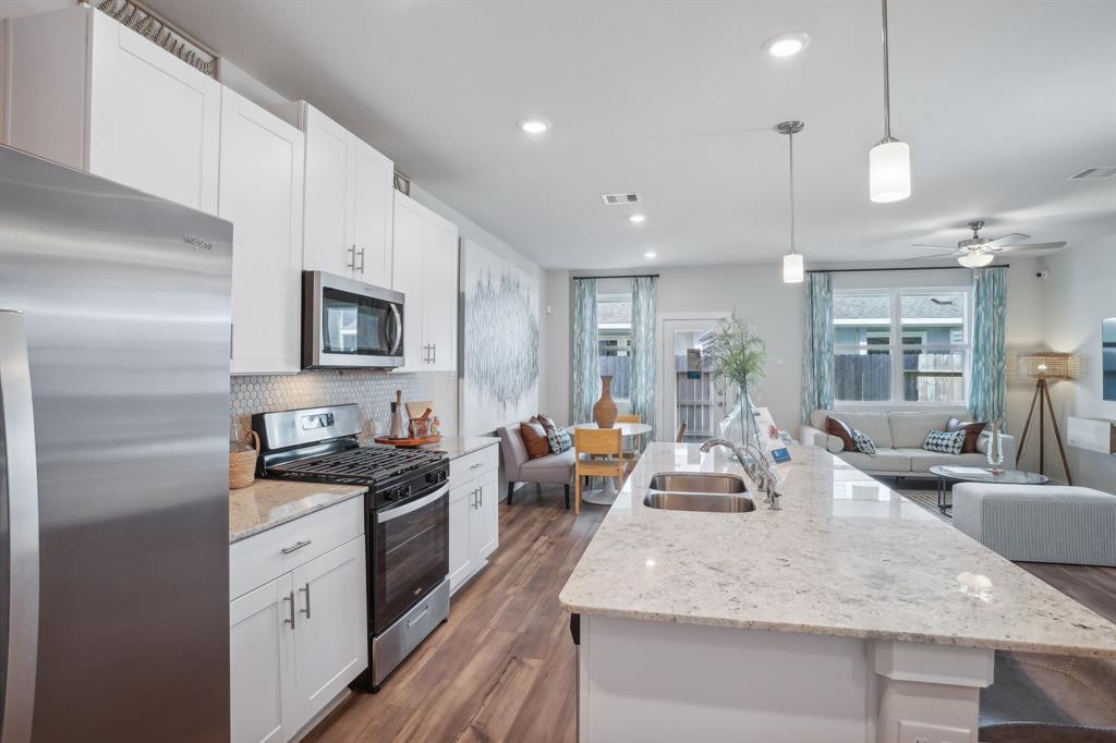 a large kitchen with stainless steel appliances granite countertop a lot of counter space and wooden floor