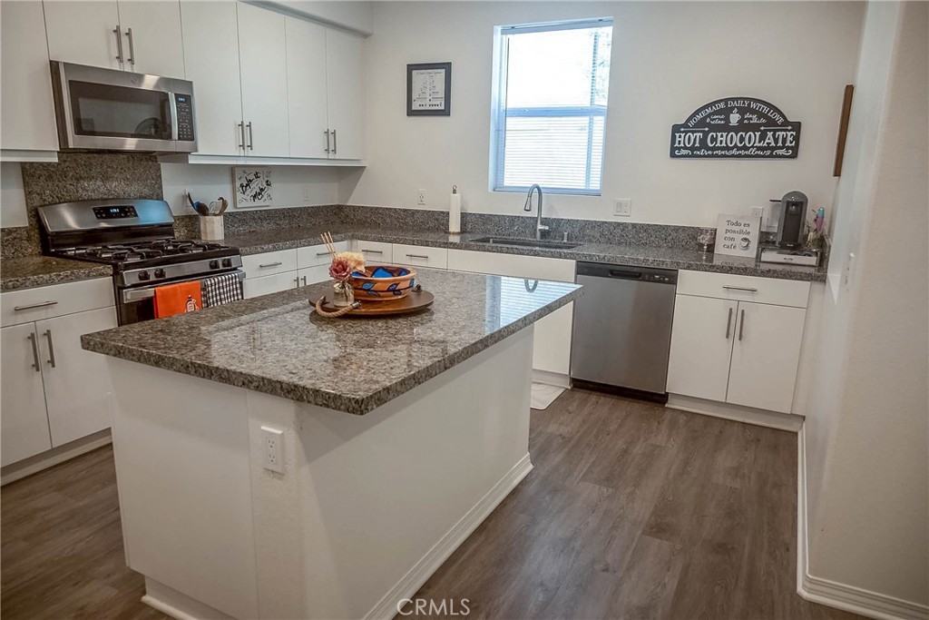 a kitchen with granite countertop a sink a stove a microwave and wooden cabinets