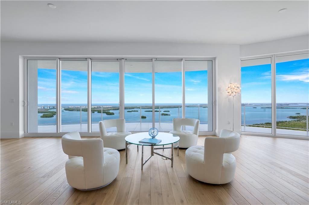 a living room with furniture a large window and wooden floor