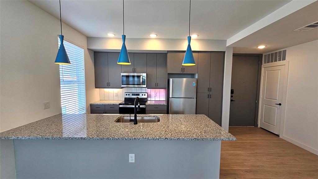 a kitchen with stainless steel appliances granite countertop a sink a refrigerator and a counter top space