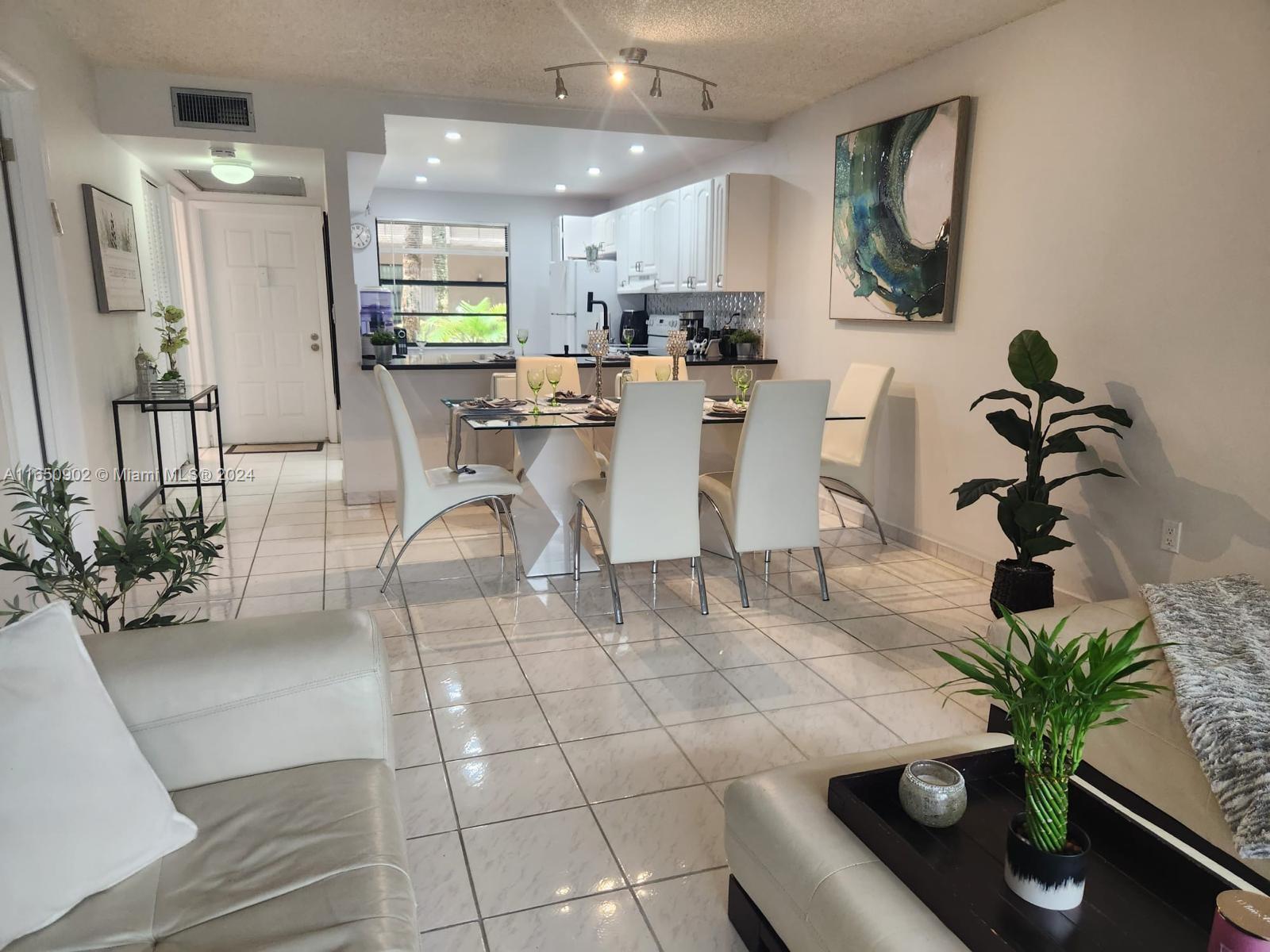 a living room with furniture a potted plant and a kitchen view