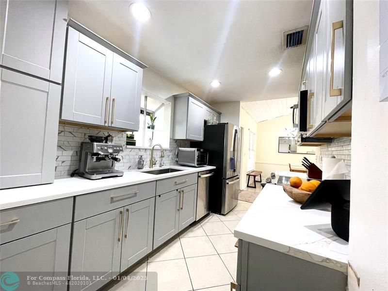 a kitchen with a sink stainless steel appliances and white cabinets