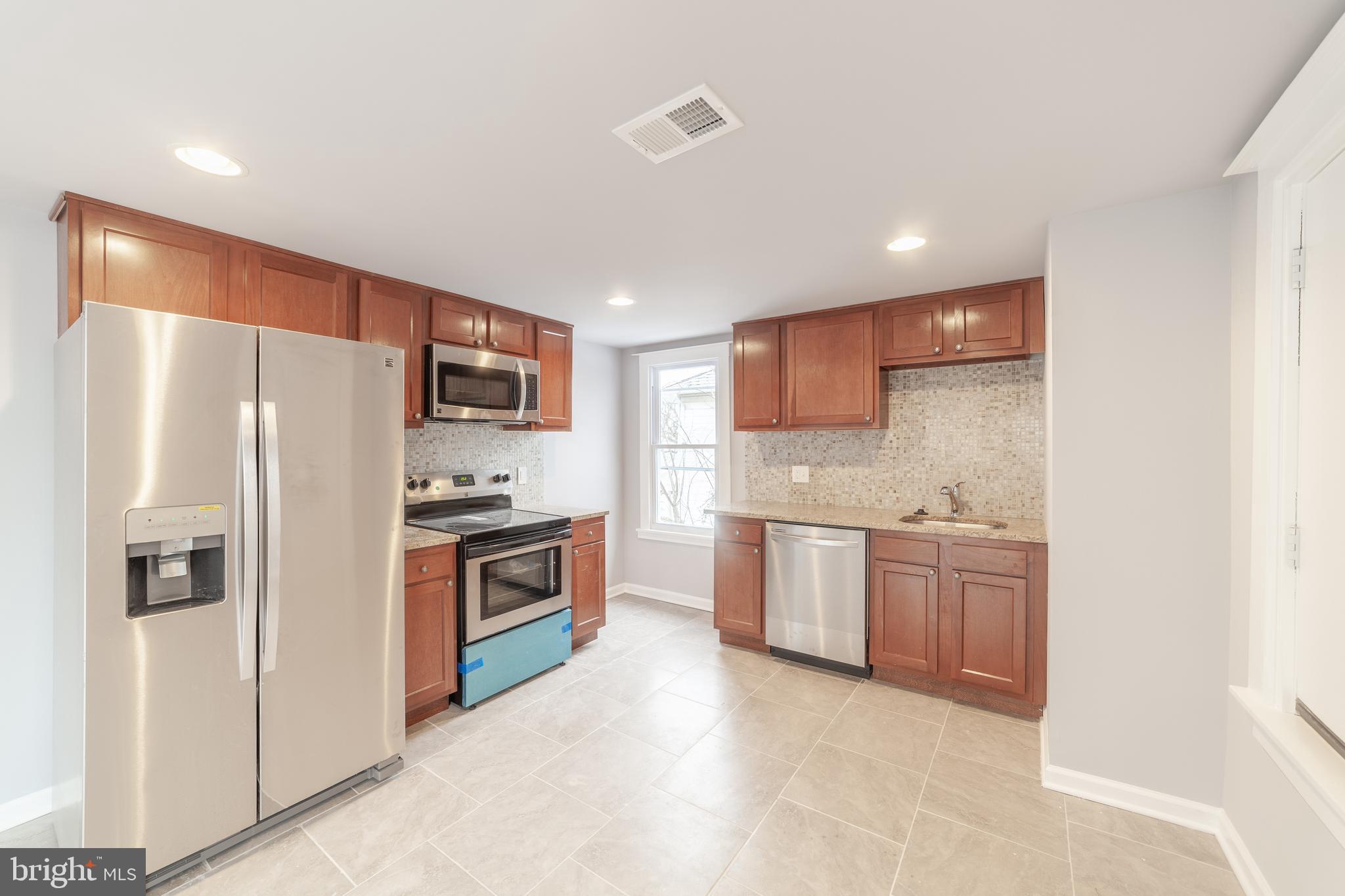 a kitchen with stainless steel appliances granite countertop a refrigerator sink and stove