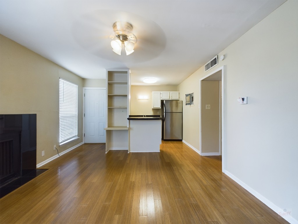 a view of a kitchen with a fridge and wooden floor