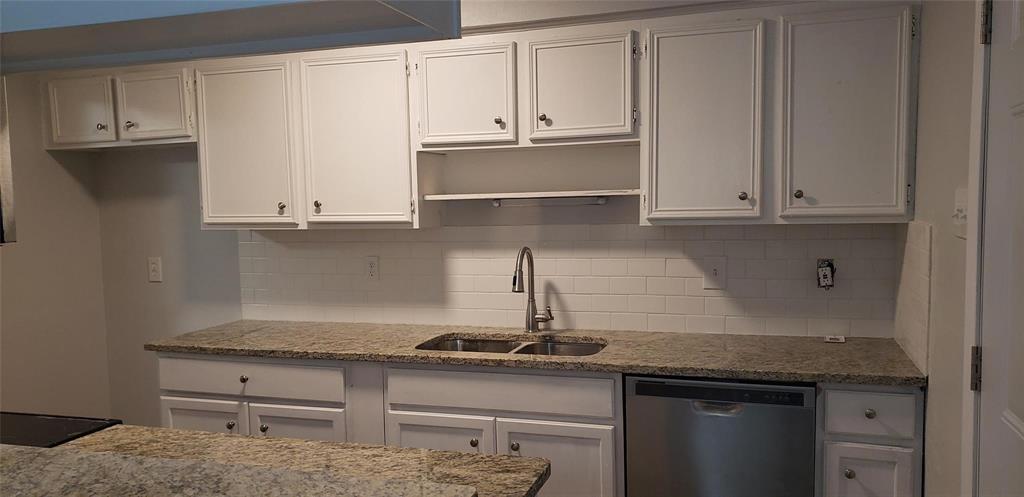 a kitchen with granite countertop white cabinets and a stove