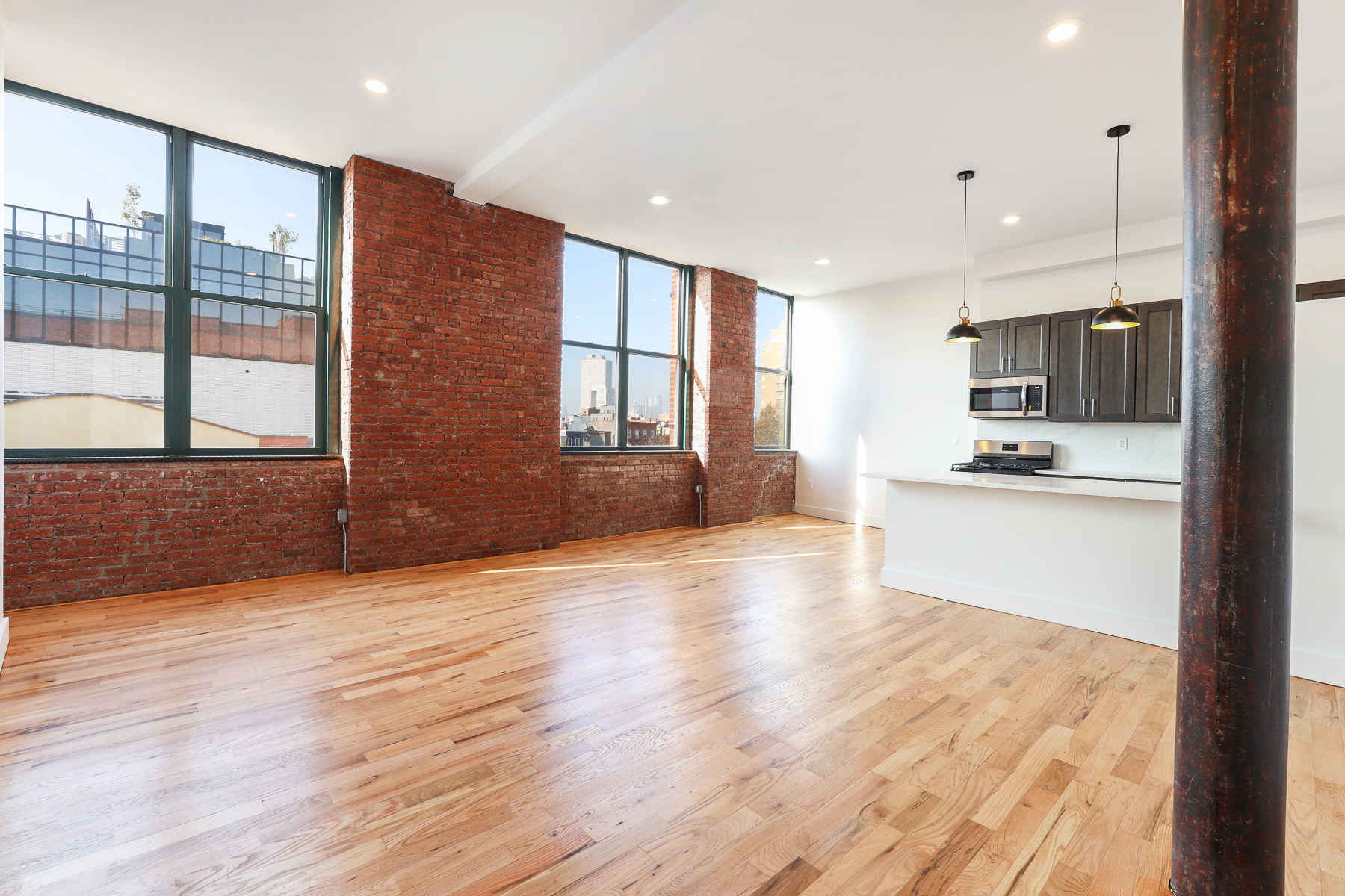 a view of a kitchen with kitchen island granite countertop wooden floor stainless steel appliances and windows