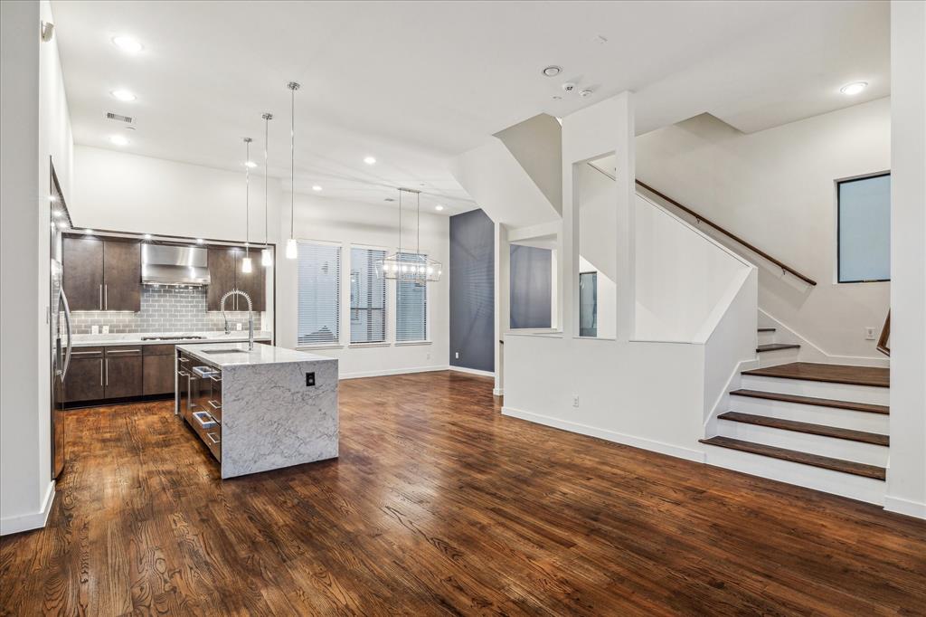 Open main living kitchen and dining space with hardwood floors, vaulted ceiling and plenty of natural light.