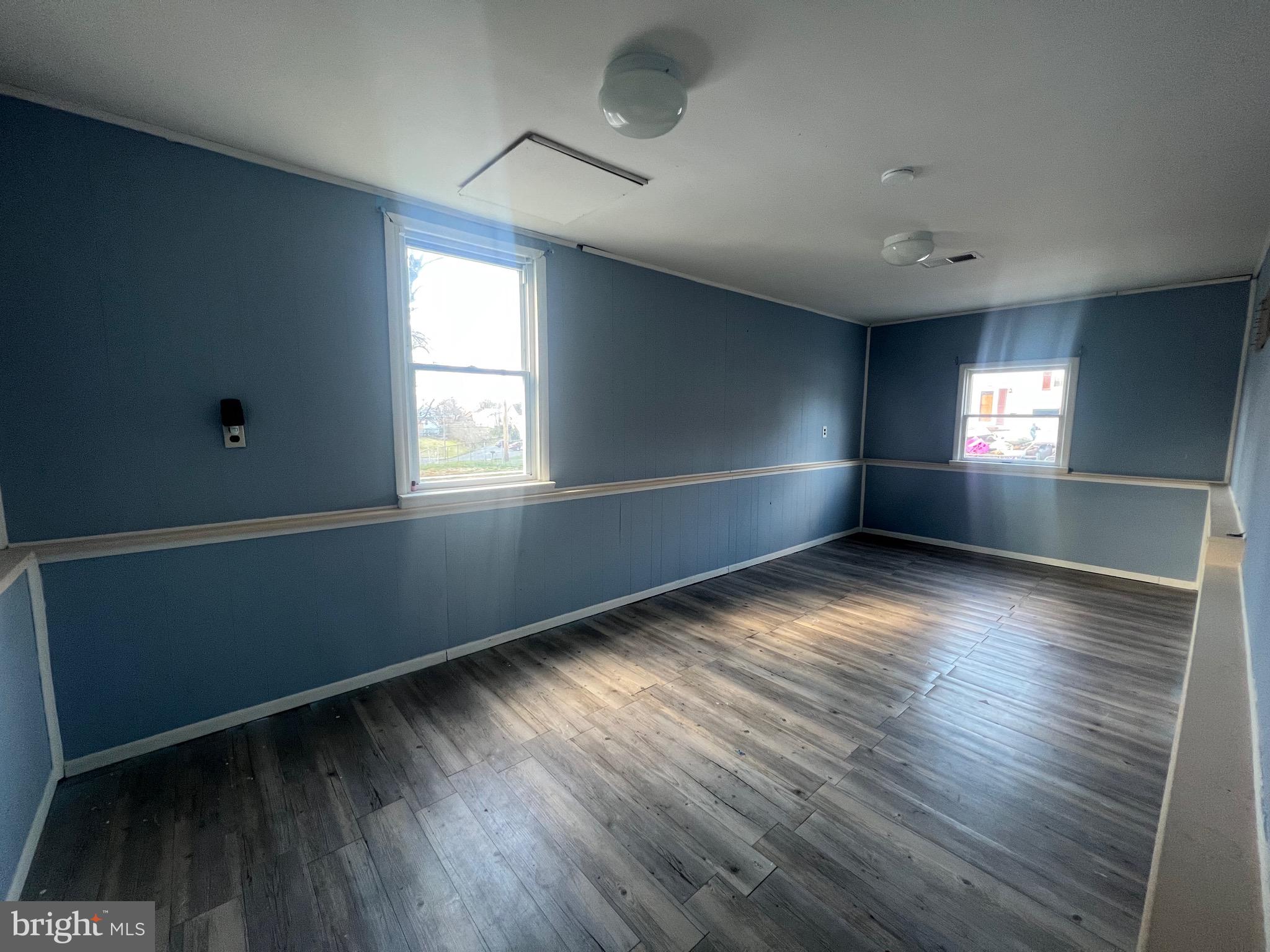 an empty room with wooden floor and windows