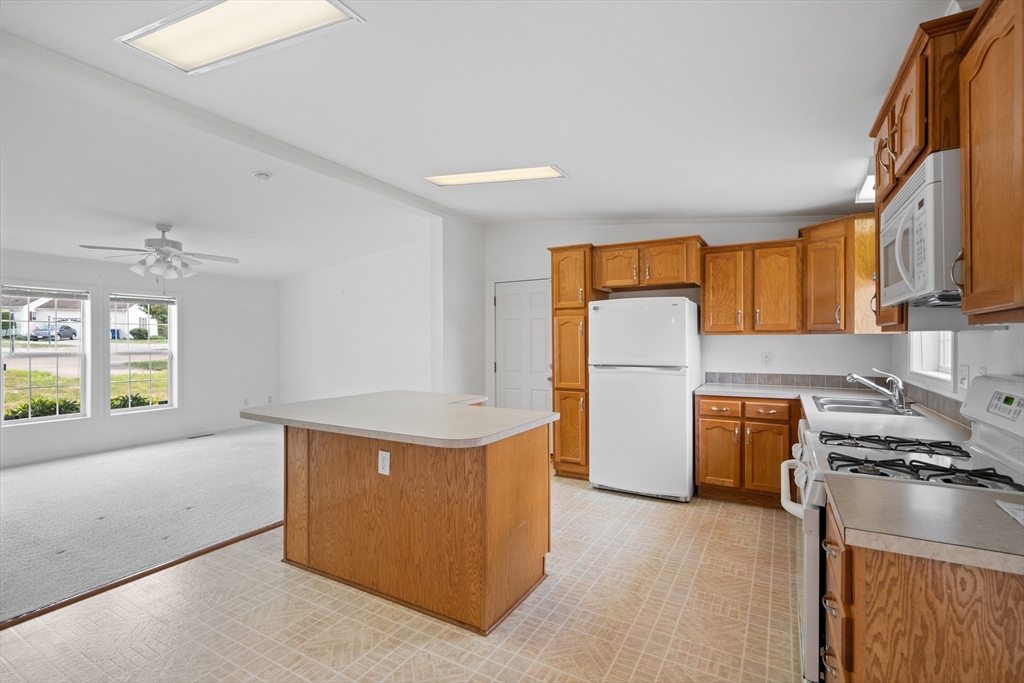 a kitchen with a refrigerator a stove top oven a sink dishwasher and wooden cabinets