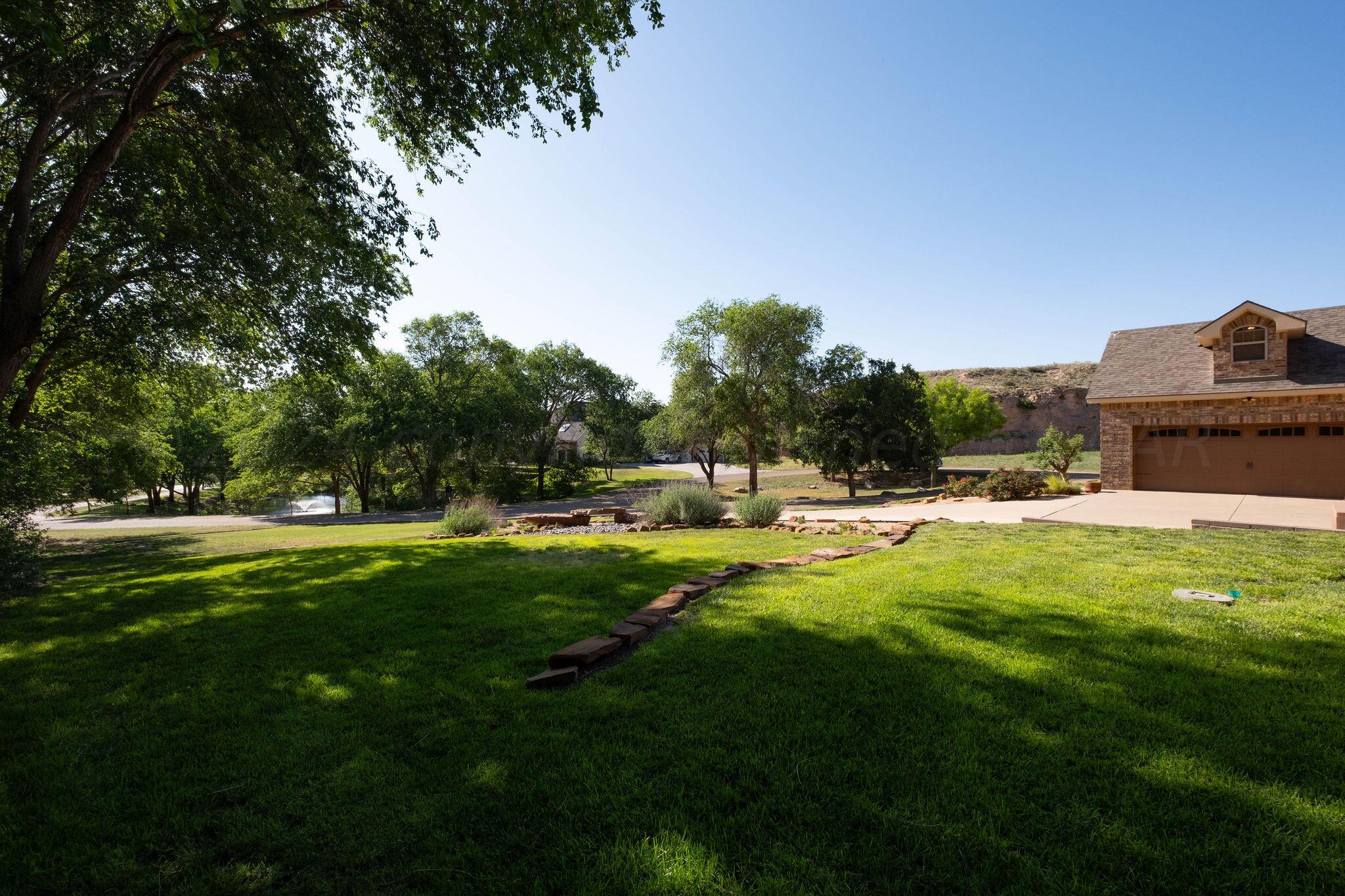 a swimming pool with lots of green space and trees in the background