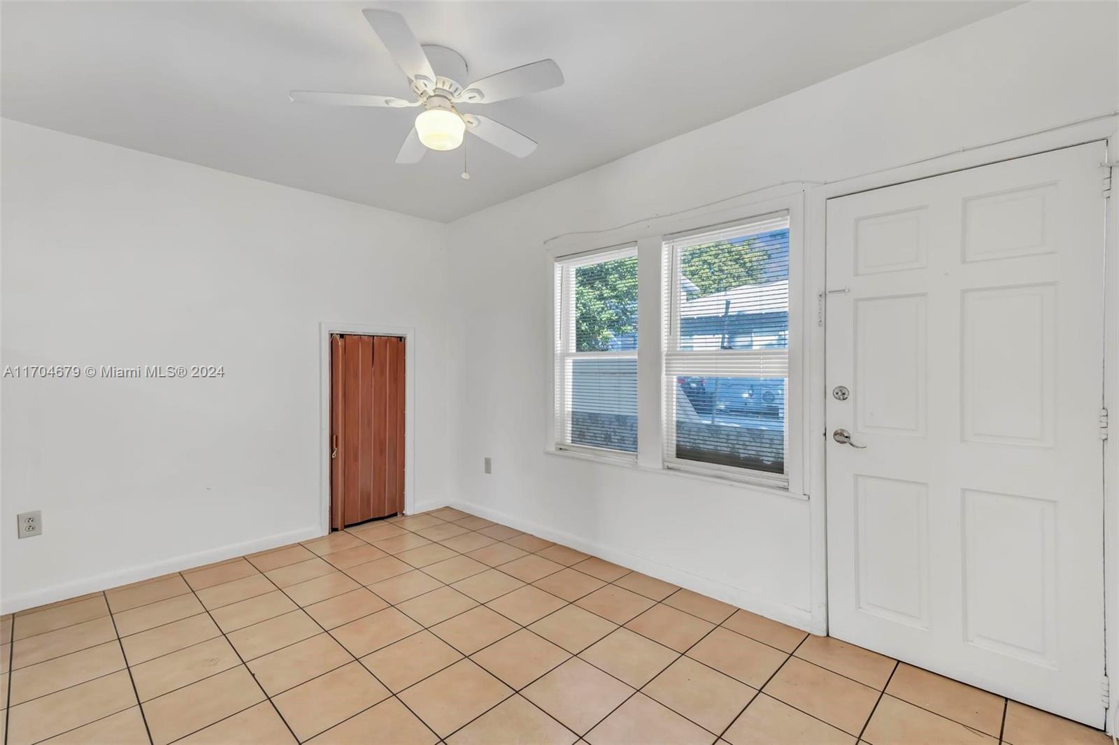 a view of an empty room with window and chandelier fan