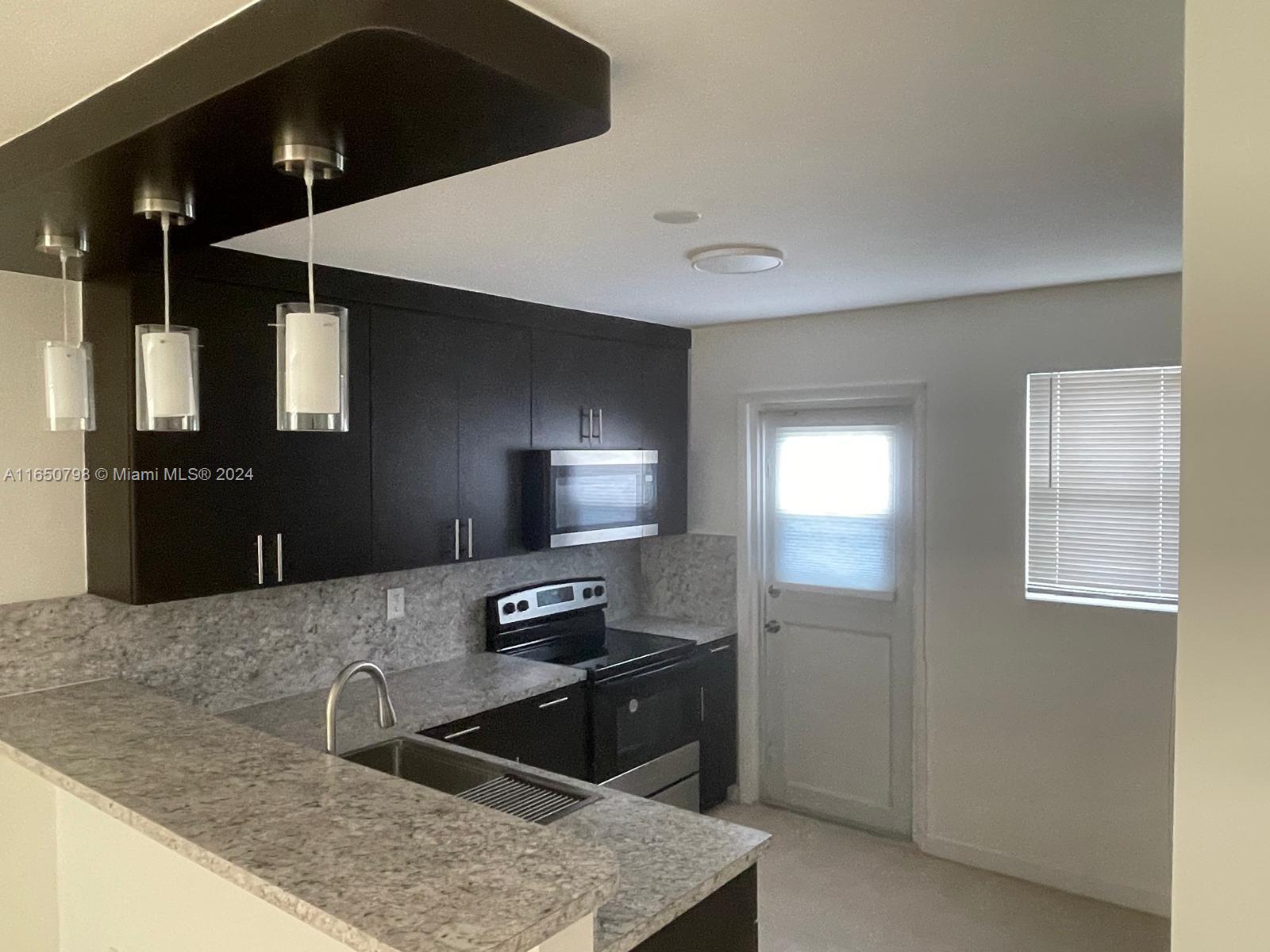 a kitchen with stainless steel appliances kitchen island granite countertop a refrigerator and a sink